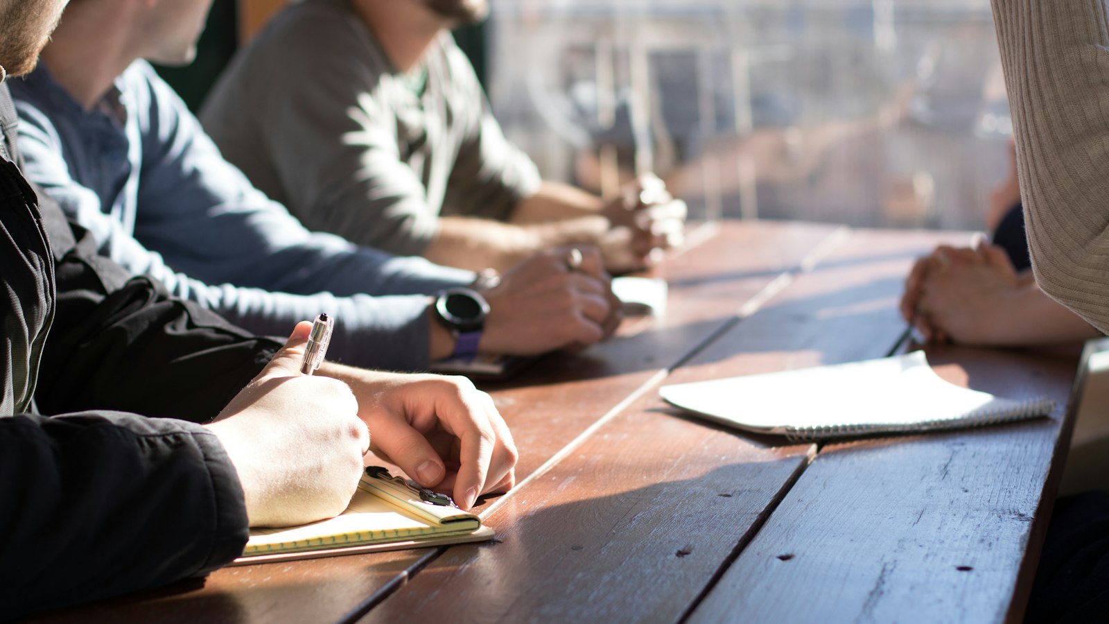 Personnes assises autour d'une table avec des stylos